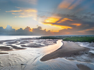 The beautiful colors at sunrise create a peaceful atmosphere, and the reflection of light on the river near the estuary adds to the vibrant morning ambiance © HeinrichDengi