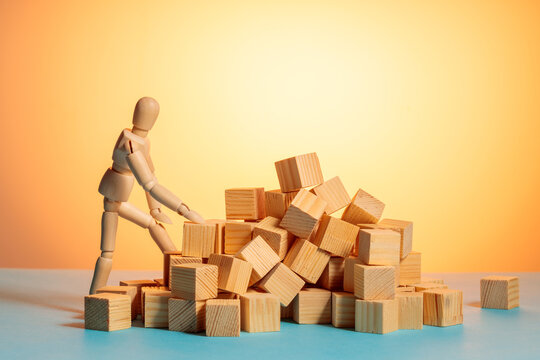 Wooden mannequin looking over scattered wooden blocks, sorting chaos concept