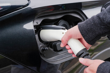 The hand of the driver to connect the EV charging plug