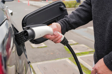 The hand of the driver to connect the EV charging plug