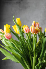 Naklejka premium bouquet of yellow and pink tulips on a grey background