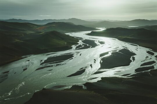 Aerial view of a winding river flowing through mountainous terrain under overcast skies