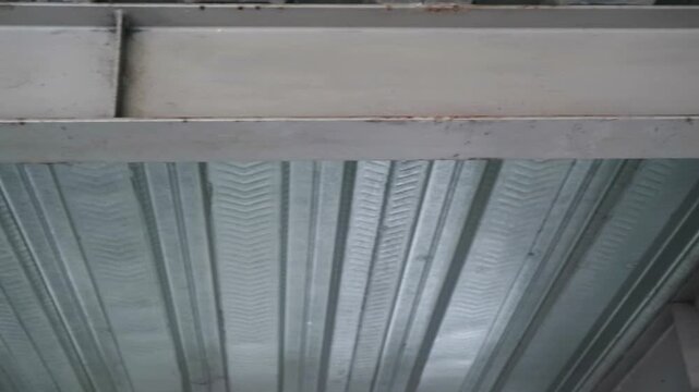 Close-up of a metal ceiling with a patterned design, featuring corrugated panels and a raised seam, showcasing a textured, industrial-style aesthetic