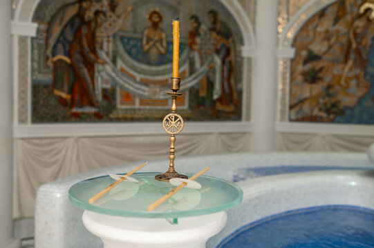 Golden Candlestick with Chi Rho Symbol and Wax Candles Near a Baptismal Font in an Orthodox Church