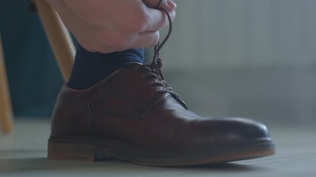 Gentle Shoe Tying. Meticulous Fingers Tighten Laces On Refined Shoe With Concentration. Man Carefully Works On Tying His Leather Shoe Laces In Softly Lit Room Before Starting His Day