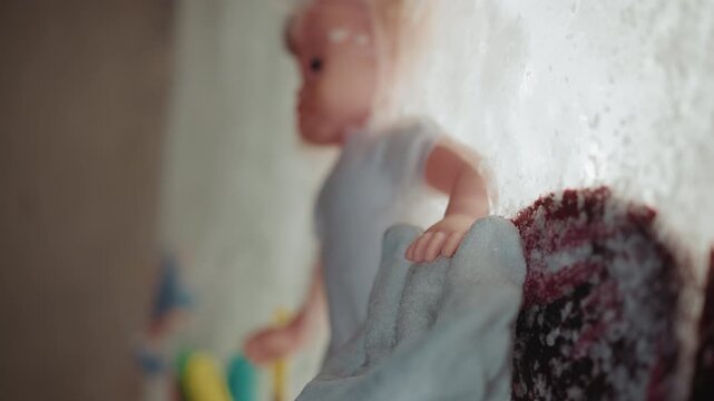 Doll clutching blanket in nuclear winter, worn plush hugged like comforter against frosted backdrop, threadbare fabric and ash dust detail, intimate closeup evokes shelter, resilience, and fragile
