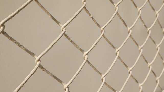 Golden brown chain link fence mesh pattern creating geometric diamond grid texture with soft bokeh background