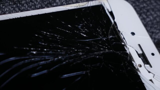 Broken cracked smartphone screen Phone red on dark fabric background, shattered glass display damage concept