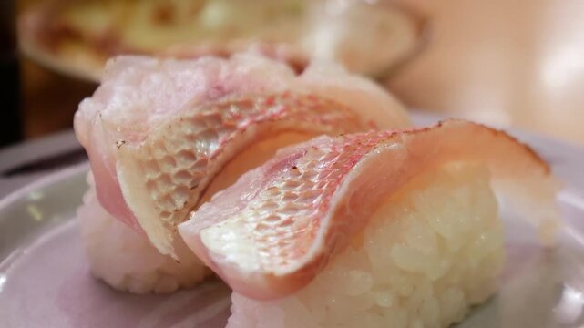 Fresh white fish nigiri sushi with skin-on snapper or sea bream on ceramic plate, Japanese traditional cuisine