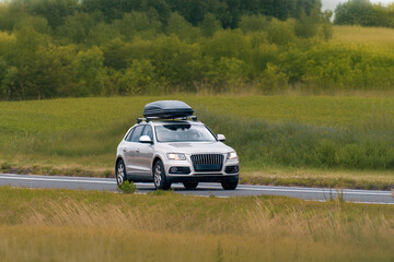 Fototapeta premium Modern White Crossover Driving with Roof Cargo Carrier