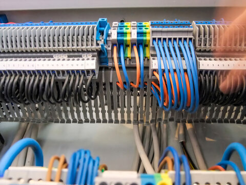 Neatly organized wiring shows black, blue, and orange wires connected to terminal blocks in an electrical panel.