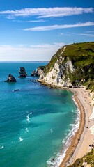 Obraz premium Coastal scene with cliffs, beach, turquoise water, and blue sky