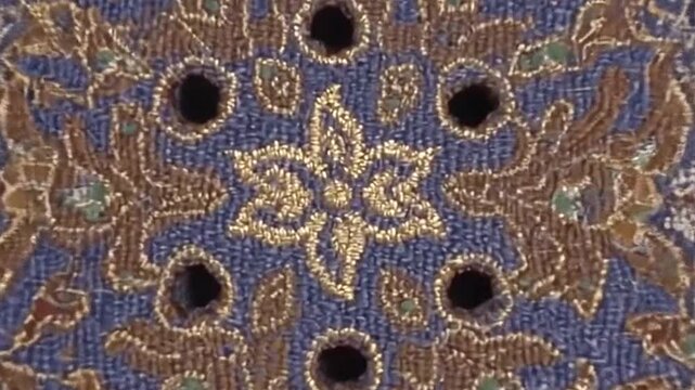 Intricate circular embroidery with gold and blue floral motifs