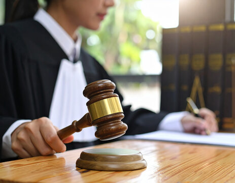 La mano de una jueza con toga negra sostiene un mazo de juez sobre la mesa del tribunal en juicio, concepto de justicia, ley, sistema judicial, autoridad legal y veredicto judicial