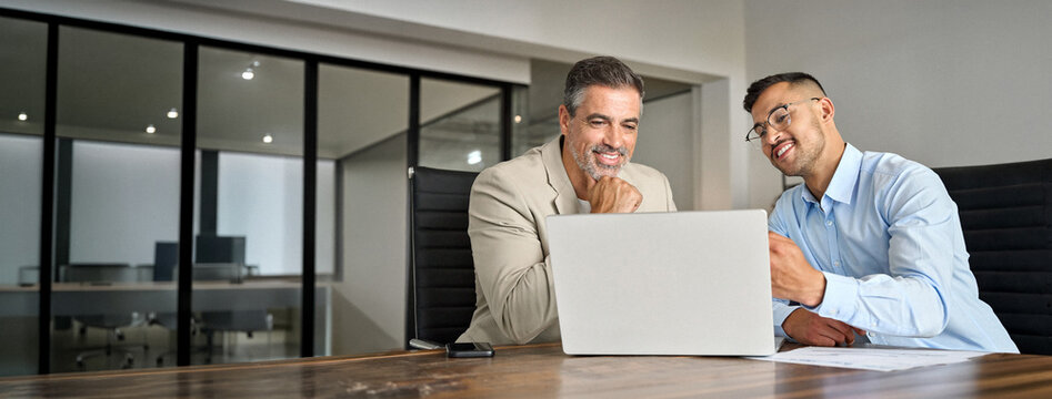 Busy smiling business men entrepreneurs talking using laptop, business team of two executive managers working on computer in office managing data at meeting. Financial advisory investment consulting.