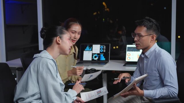 Asian business team brainstorming and arguing during a late meeting. They finally resolve the conflict, celebrate the success, and applaud together