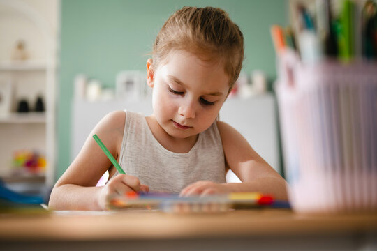 Little girl drawing at a table, at home. Education and parenting