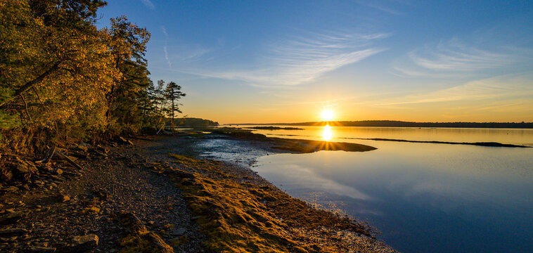 Golden Sunset Over Calm Coastal Waters and Rocky Shoreline