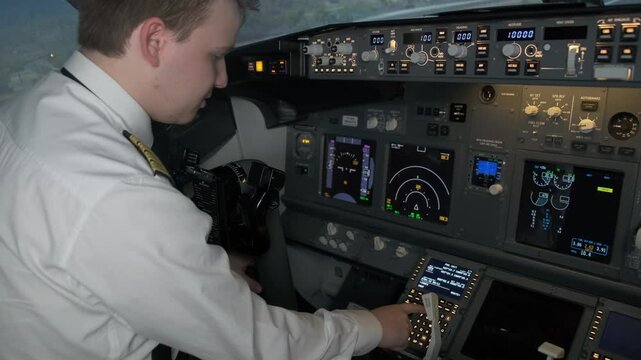 Young captain in uniform inputs flight plan on control display unit. Pilot engages in preparation process of aircraft for journey