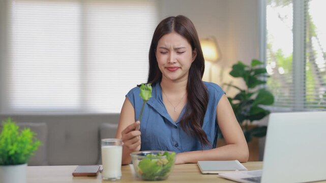 Unhappy young asian woman feeling bored and disgusted with her healthy salad diet. Unpleasant meal choice for weight loss and wellness