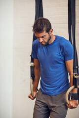 Man, fitness or gymnastics with rings in gym for workout, strength training or stability with cardio. Active, male person or exercise with balance for strong core or muscle gain at indoor health club