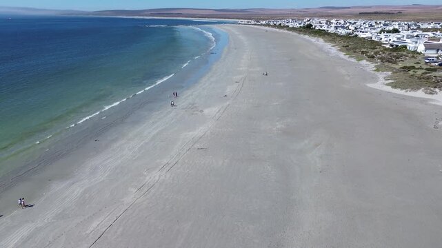 Camera panning up along the beach of Paternoster. Paternoster picturesque seaside tourist town with traditional white fishing cottages and houses. 4K Aerial Video.