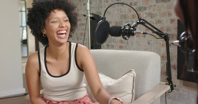 Adult African descent woman laughing, holding tablet on set mic, arm reaching greeting, copy space