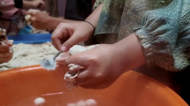Hands shaping dough into small meatballs. 