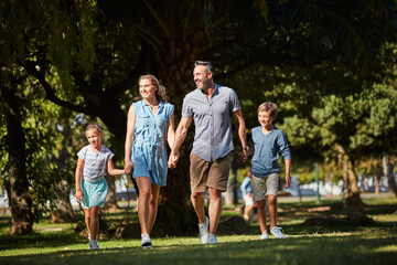 Happy family, parents and holding hands with kids outdoor for care, laugh and support on holiday. Father, mother and children at park with connection, funny and walk together on vacation for travel