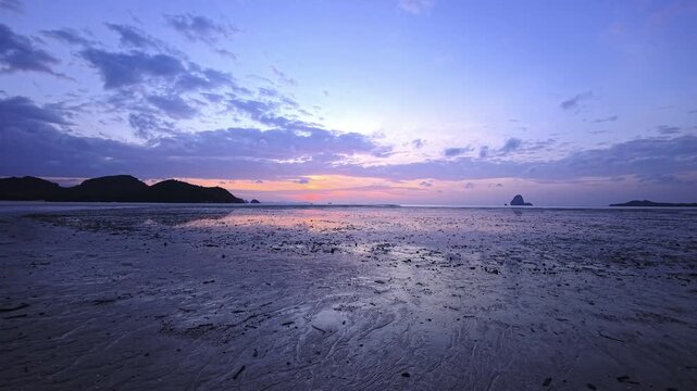 Shallow coastal flats stretching toward a solitary offshore limestone island in Thailand