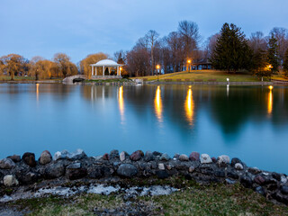 Obraz premium Upper Onondaga Park reflects the gazebo and stone bridge in soft twilight that invites travelers to pause, breathe, and discover the peaceful charm of Syracuse’s historic parkland