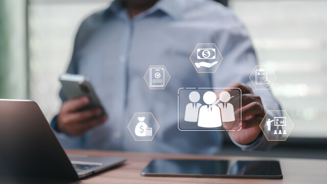 Professional businessman manages human resources digital icons. Finance, insurance, recruitment symbols float above laptop. Modern technology facilitates efficient workforce management, payroll