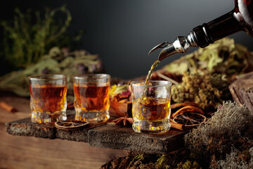 Herbal bitter liqueur is poured from a vintage bottle into a glass.