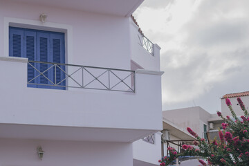 traditional cycladic architecture with white washed wall, blue window shutters and blooming...