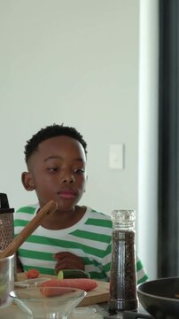 Vertical video: Grinding pepper mom in peach top seasoning pan mixing adding sauce on stove for son