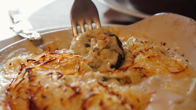Tasty canelones with spinach, cheese and bechamel sauce in an Italian restaurant. Close up of creamy texture of canelones.