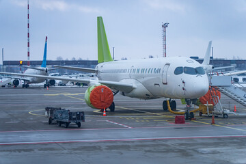 Passenger jet on airport apron with engine intake covers, tow bar and service platform in cold season, illustrating ground handling workflow, maintenance protection and aviation operations theme