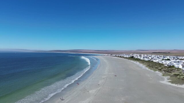 Camera panning left to right over the beach and town of Paternoster. Paternoster picturesque seaside tourist town with traditional white fishing cottages and houses. 4K Aerial Video.