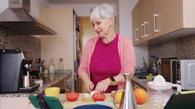 Senior woman vlogging cooking tutorial in kitchen