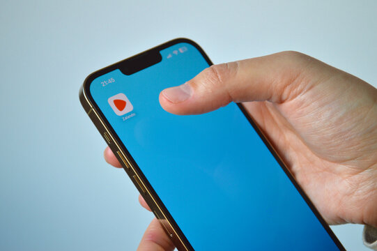 Close-up of a person holding a modern smartphone with the Zalando mobile app icon visible on a bright blue digital screen display in a minimalist indoor setting.