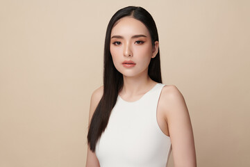 Obraz premium A beautiful young Asian woman with clean, fresh skin against a beige background. Skincare, facial treatment, cosmetology, beauty, and spa. An elegant portrait of an Asian woman.