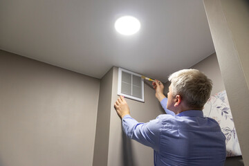 A person cleaning with a brush an HVAC return air vent grille and duct. Maintenance