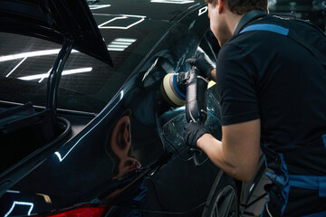 Obraz premium Automobile detailer polishing auto body exterior surface with orbital buffer