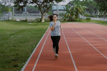 Obraz premium Attractive young beautiful asian woman wearing sportswear running at sport stadium. Fit woman jogging outdoor, workout exercise in the morning. Healthy and active lifestyle concept.