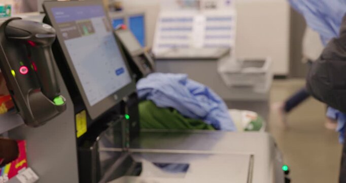 Customer scanning shirt at self checkout kiosk in supermarket