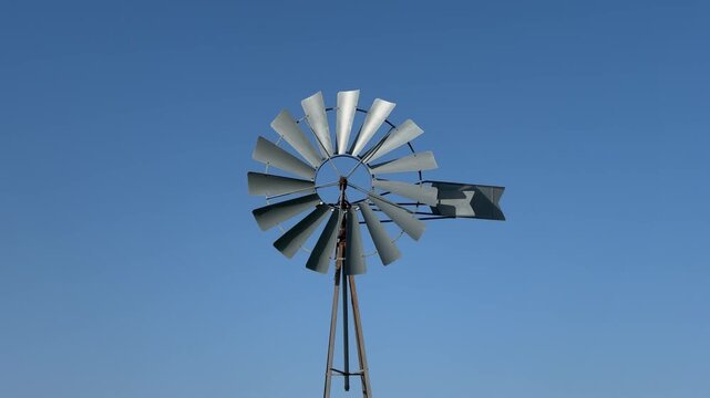 Traditional metal windmill spinning against a clear blue sky
