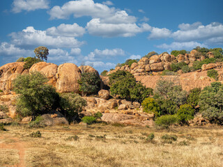 African Savanna Landscape with Massive Granite Rock Formations Under a Bright Blue Cloudy Sky