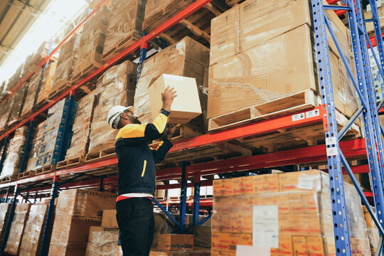 Male workers strength lift heavy boxes merchandise on their shoulders move them  distant shelves and risk injury or accidents from repeatedly lifting heavy items without weight lifting equipment.