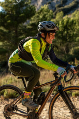 Woman enjoying an active day cycling a gravel bike through a dry mountain landscape in alicante, costa blanca, finding joy in nature and outdoor sport - stock photo