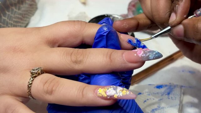 Technician adding fine details to 3D nail art using precision tools, creating unique textured patterns.